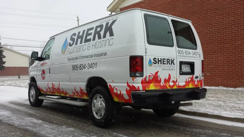 Sherk Plumbing & Heating service van parked beside a red brick building, featuring flame decals and company branding